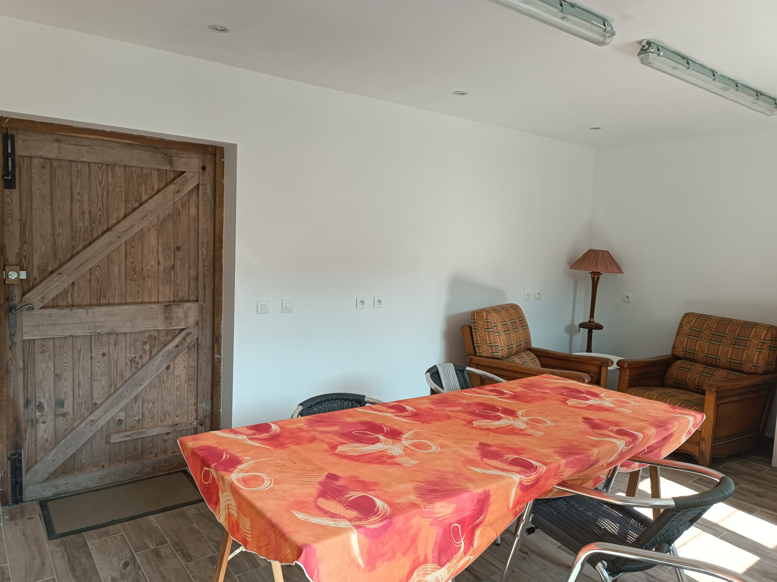 Salle commune, espace repas et détente pour les cyclistes Espace intérieur convivial avec une grande table et des fauteuils pour les hôtes en bivouac au Manoir de Kerledan.