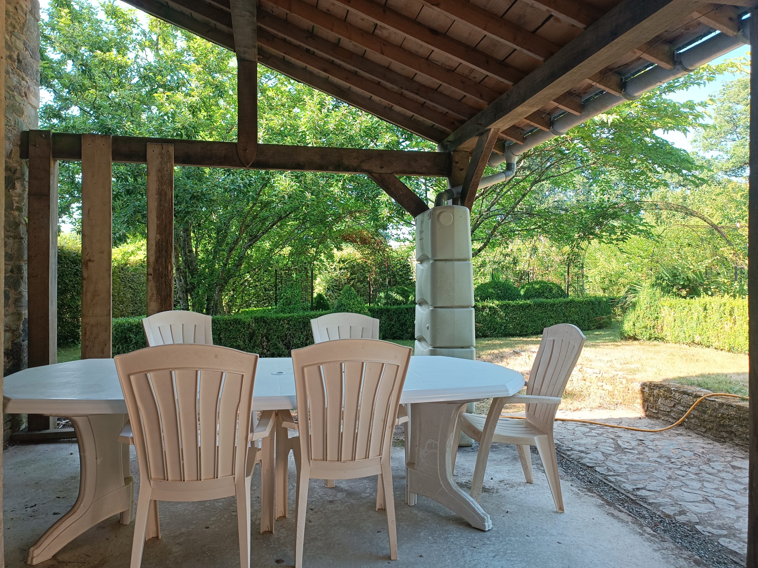 Terrasse couverte et salon de jardin donnant sur le parc Terrasse en bois couverte avec table de jardin et vue sur le parc arboré du Manoir de Kerledan.